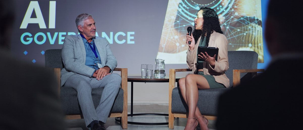 A governance discussion between colleagues, with an AI system in the room